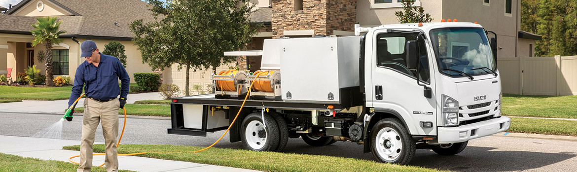 Man spraying gas in front of a 2018 Isuzu Truck N Series Gas in a neighborhood